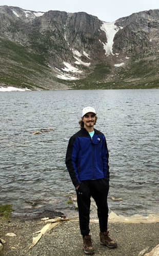 Tanner Thornton standing in front of water and mountains